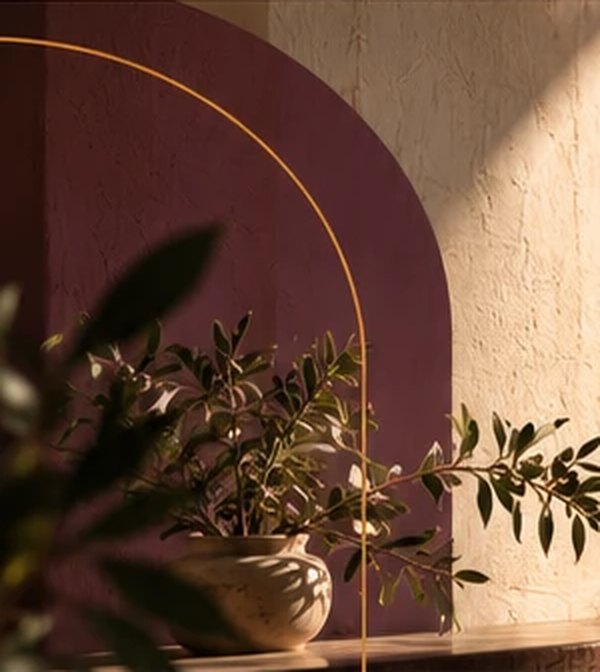 Olive branches in a stone vase against a plum-painted arch on a limewashed wall.